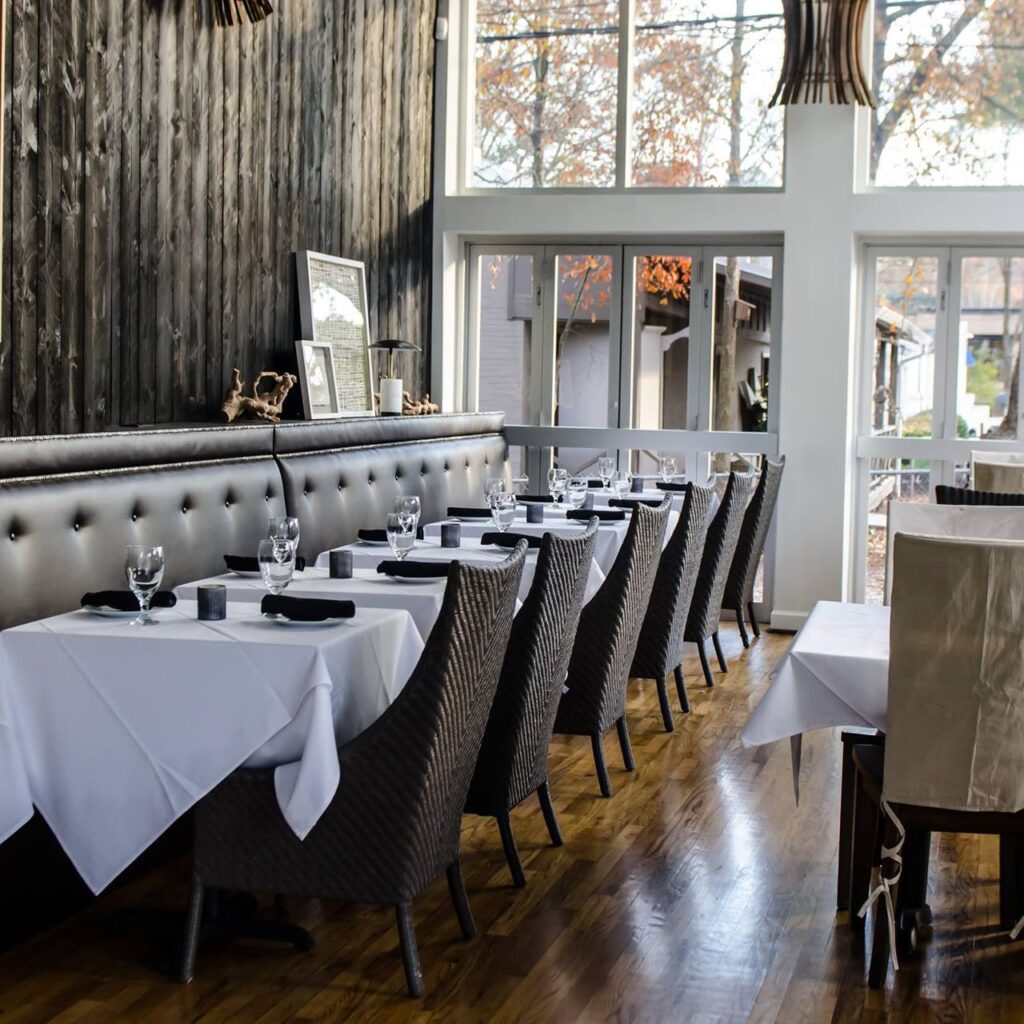 A restaurant with white tablecloths and wooden walls.