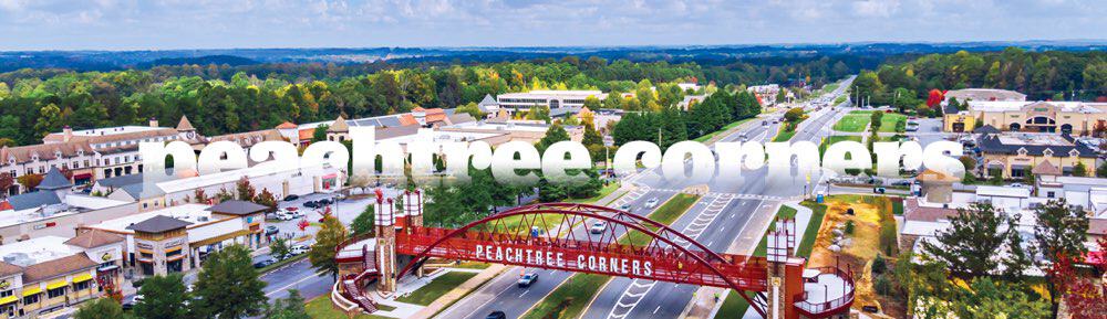 Aerial view of Peachtree Corners with a prominent sign and a commercial area surrounded by trees.